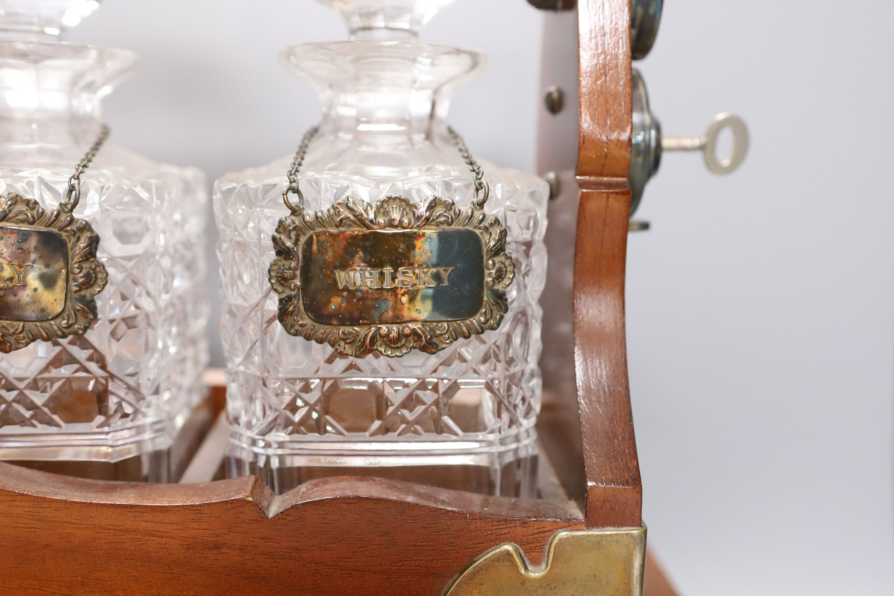 A three decanter tantalus - with labels, together with an oak canteen of table plated cutlery